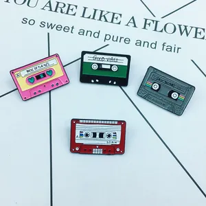 Detail of four retro cassette enamel pins with vintage text on a white display card