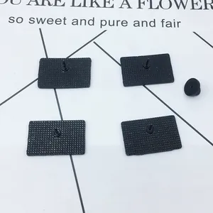 Rear view of 4 rectangular metal pins with textured surface and black rubber clutch backing