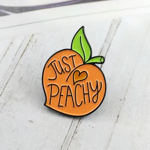 Vue détaillée du pin's en émail pêche Just Peachy avec feuilles sur bois rustique