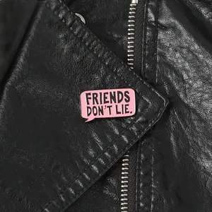 Pink enamel FRIENDS DON'T LIE speech bubble pin badge on a black leather jacket lapel