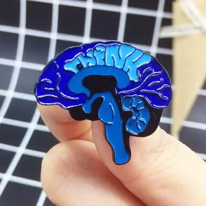 Dettaglio della spilla in smalto a forma di cervello con scritta THINK in mano