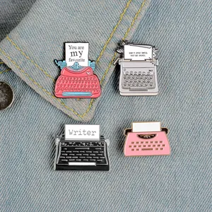 Detailed macro view of four vintage typewriter enamel pins on blue denim fabric background