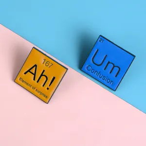 Gros plan des pin's émaillés éléments Ah et Um sur fond bicolore pastel doux