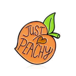 Broche en émail pêche mignonne avec détail de cœur et texte Just Peachy sur fond blanc