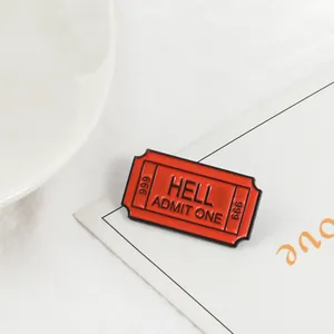 Creative red HELL ADMIT ONE ticket enamel brooch on white cardstock backdrop