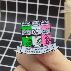 Détail de pin's en émail colorés tenus à la main avec citation inspirante she turned her cants into cans