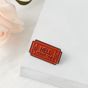 Detail of red ticket-shaped enamel pin with black HELL ADMIT ONE 666 engraving