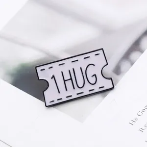 Détail d'un pin's ticket en émail blanc avec texte 1 HUG sur fond de livre ouvert