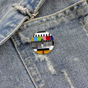 Close-up of a retro TV test pattern enamel pin on dark denim fabric showing fine details