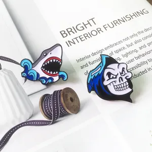 Détail des épinglettes en émail requin et crâne sur un fond de magazine ouvert