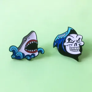 Macro de deux pins en émail avec un requin bleu et un crâne à capuche pour sac à dos