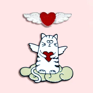 Gros plan du chat volant et des épinglettes en émail cœur sur fond rose doux