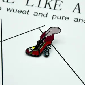 Detailed close-up of a Christmas enamel stiletto pin with feathers and red-black finish