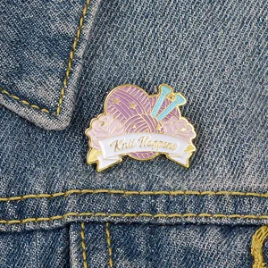 Détail d'un pin's émaillé Knit Happens sur le tissu d'une veste en jean bleue