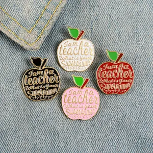 Detail of four colorful apple enamel pins with teacher slogans on denim background