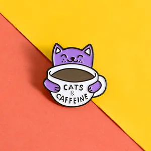 Nahaufnahme einer lila Katzen-Emaille-Anstecknadel, die eine Kaffeetasse hält