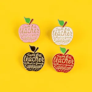 Close-up of four colorful apple enamel brooches with Teacher superpower quote on yellow background
