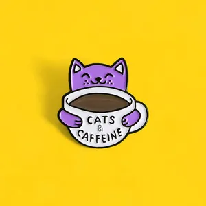 Detailaufnahme einer lila Emaille-Anstecknadel mit Katze und Kaffeetasse auf Gelb