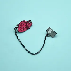 Detailed view of enamel heart brooch connected by a chain to a display monitor pin