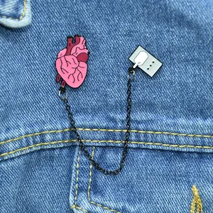 Creative anatomical heart enamel brooch with chain on blue denim background