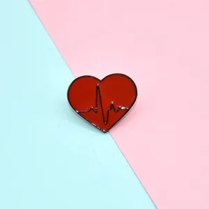 Detail of red heart-shaped enamel brooch with black ECG pulse line on vibrant background