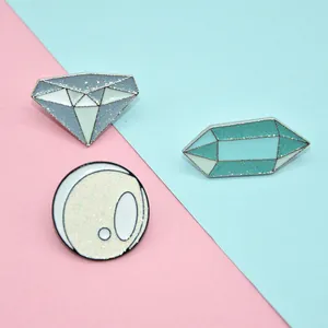 Detail of glitter enamel pins featuring diamond and crystal shapes on pastel background