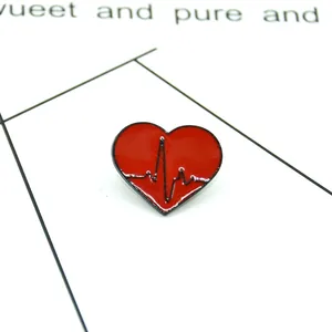 Close-up of red heart enamel pin with black heartbeat ECG line and glossy finish