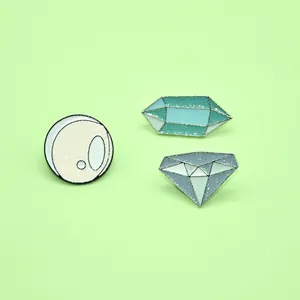 Detail of glittery blue and yellow enamel pins set in diamond and crystal ball shapes
