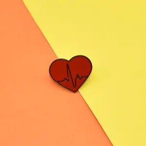 Macro shot of a red heart enamel pin with black EKG line on a vibrant dual-tone background