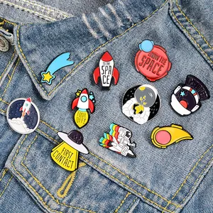 Lot de pins émaillés astronaute et fusée spatiale sur une veste en jean bleue