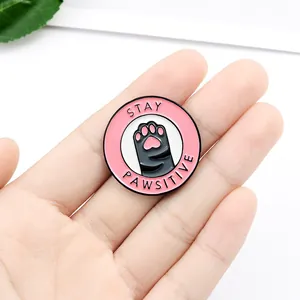 Pin's émaillé rose Stay Pawsitive en forme de patte de chat montrant sa taille réelle