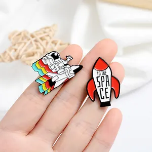 Lot de pins émaillés astronaute et fusée 'To The Space' présentés à la main