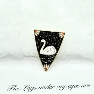 Detail of triangular black enamel swan brooch with Forever gold text and stars