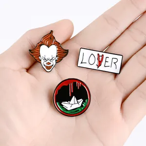 Three-piece horror movie enamel pin set featuring clown face and paper boat designs