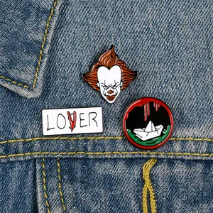 Close-up of three horror movie clown enamel pins on a blue denim jacket pocket