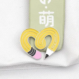 Close-up of heart-shaped enamel pin featuring yellow pencil and Make More Art text