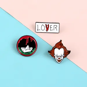 Detailed view of three horror movie enamel pins featuring clown and paper boat motifs