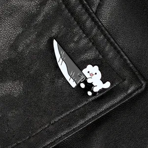 Close-up of a cute cartoon white cat enamel pin holding a knife on black leather