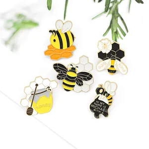Set of five cute bee enamel pins including honeycomb and honey jar on white background