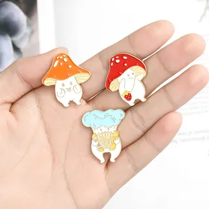 Süßes Emaille-Pin-Set mit Pilz- und Erdbeermotiven in der Hand zur Größendarstellung