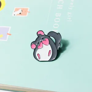 Détail d'un pin's Totoro mignon en émail avec des cœurs roses sur un fond vert pastel