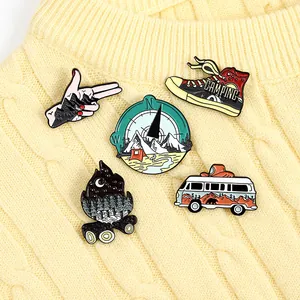 Five-piece metal enamel pin set featuring camping themes on a knit sweater background