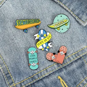Détail de cinq broches émaillées de skateboard avec slogans colorés sur denim