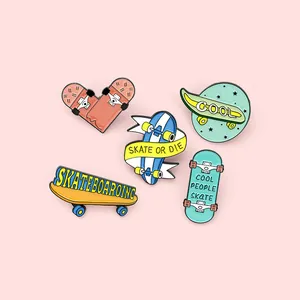Détail de cinq pin's émaillés colorés sur le thème du skate sur fond rose pastel