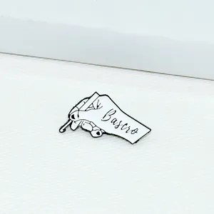 Close-up of white enamel hand pin holding a crochet hook on textured white fabric