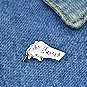 Graffiti style hand and pen enamel pin on blue denim fabric background for clothing