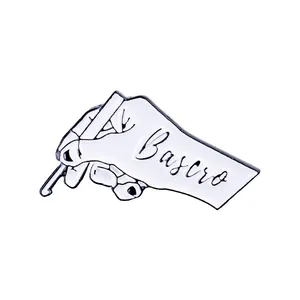 Detail shot of a white enamel pin with hand gesture and Bascro engraving for clothing