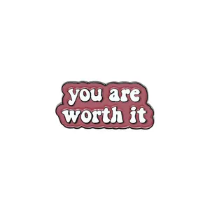 Détail de la broche en émail rouge foncé avec inscription 'you are worth it' pour vêtements