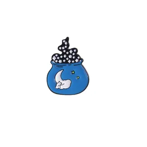 Detailed view of a blue enamel magic cauldron pin with moon and stars patterns