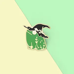 Detailed view of frog enamel pin wearing a black witch hat with golden metal edges